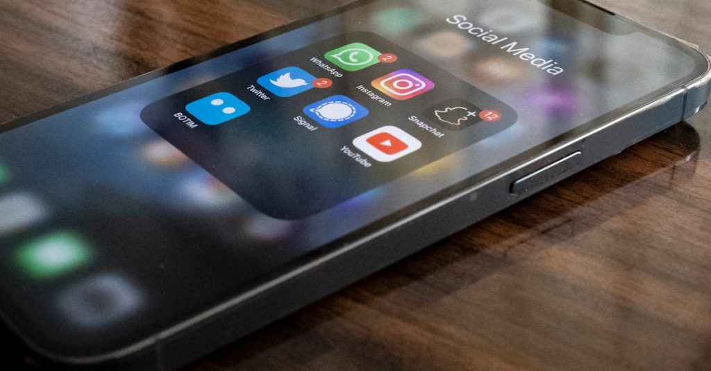 Close-up of smartphone on table showing various social media app icons including WhatsApp and Instagram.